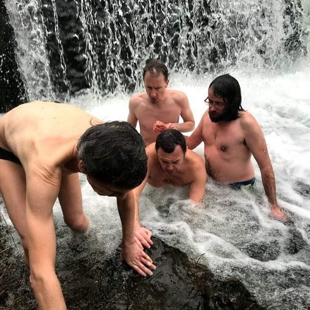 Photo de plusieurs hommes en maillot de bain dont Nico handi routard dans une rivière gelée et sous une cascade